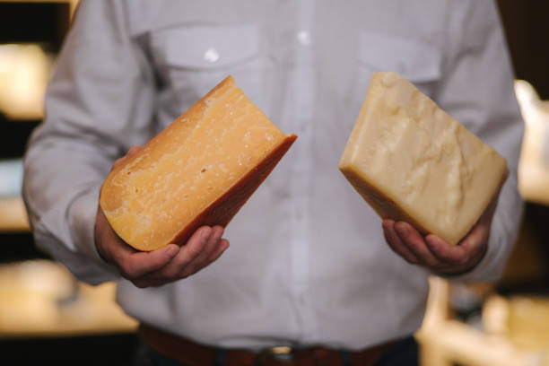 istock Handsome bearded man hold different types of aged cheese in hands at cheese store 1206085633
