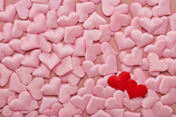 istock Two red hearts on valentine background from pink silk hearts. Valentine's Day. Top view with copy space. Hearts background. 1206093955