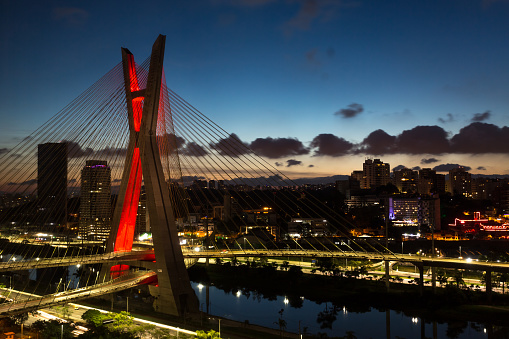 The Octavio Frias de Oliveira bridge is a cable-stayed bridge in Sao Paulo at night, Brazil over the Pinheiros River at sunset.