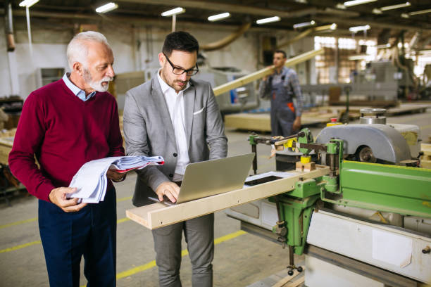 istock Two managers talking about project with manual worker with disabilities inside factory 1206100626
