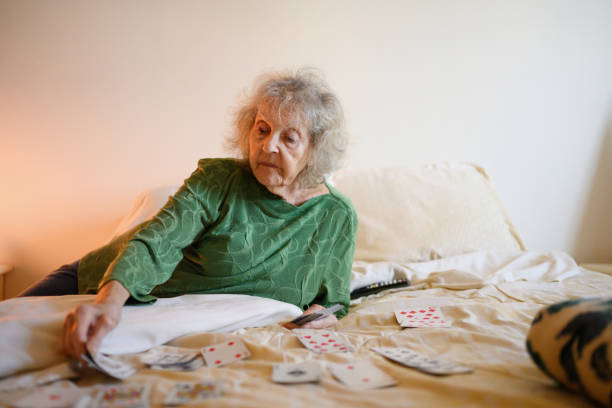 senior grandmother playing solitare card game in bedroom - solitare imagens e fotografias de stock