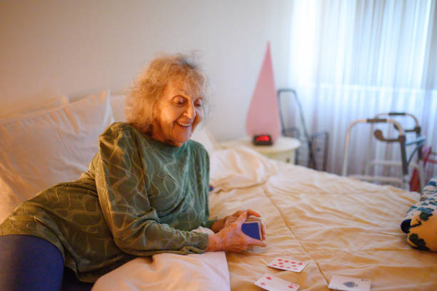 retired senior woman playing solitare card game in bedroom - solitare imagens e fotografias de stock