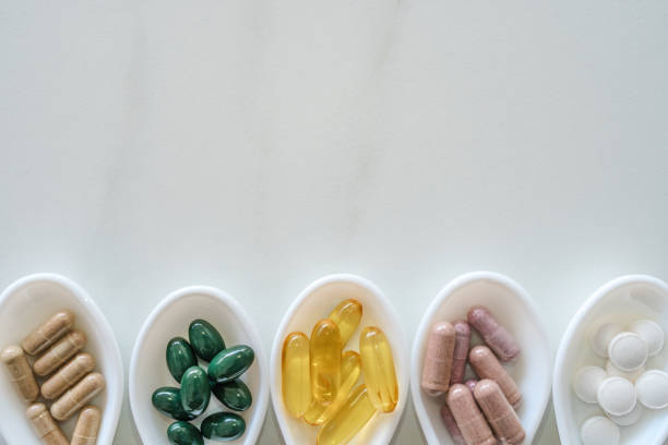大理石のテクスチャの背景のフレームとして白いスプーンに天然ビタミンサプリメントのトップビュー。健康的な食事のライフスタイルトレンドの概念。 - capsule pill white nutritional supplement ストックフォトと画像