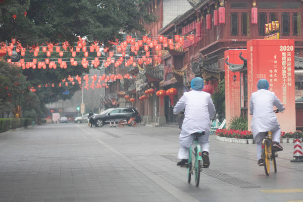 chinesischer arzt trägt chirurgische maske reitrad auf der straße - senior women capsule senior adult medicine stock-fotos und bilder