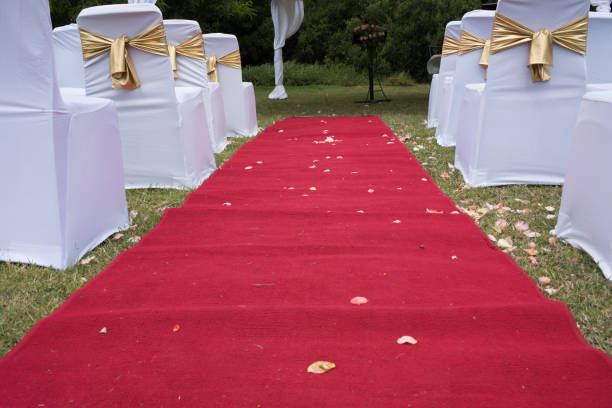 Red carpet on lawn with chairs packed for marriage service