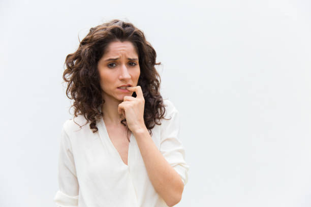 Thoughtful young woman biting finger. Worried female thinking something while posing in studio. Searching decision, stress concept