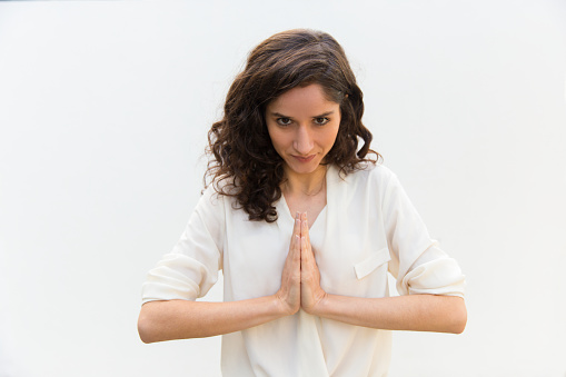 Unrecognizable caucasian female is doing Reverse Anjali Mudra in front of white background. Meditation and yoga concept.