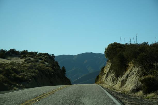 Empty Road Heading Up Hill Against Clear Blue Sky
