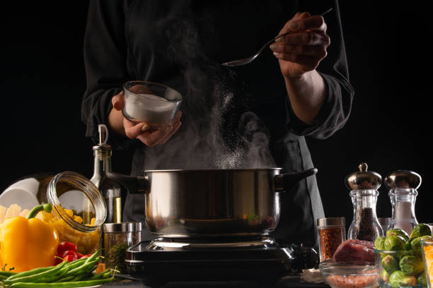 istock Culinary specialist or chef cooks soup or Italian pasta, from dressing. Heating a pan with steam, against a background of vegetables. Recipe book, cooking, gastronomy, freezing in motion. 1206136206