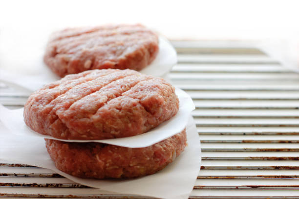 Two raw red meat burgers for hamburgers of minced ground beef or pork ready for cooking isolated on white background, top view