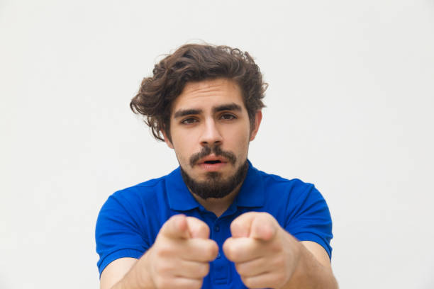 Front view of bearded man pointing to camera with forefingers. Studio shot of handsome stylish guy gesturing. Choosing you concept