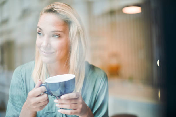 istock Woman holding a cup of coffee and looking through window. 1206150556
