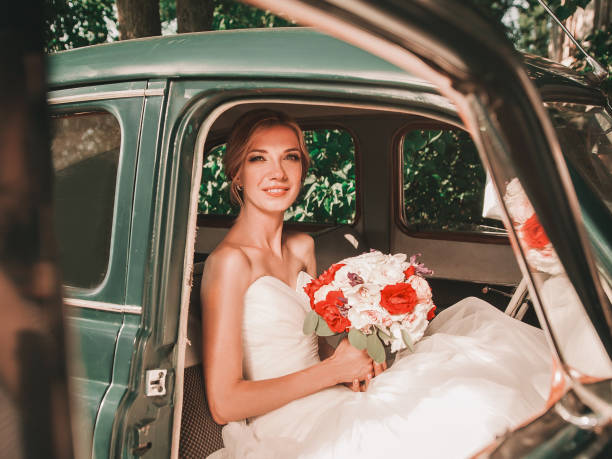 istock happy bride with bouquet sitting in car. 1206153619