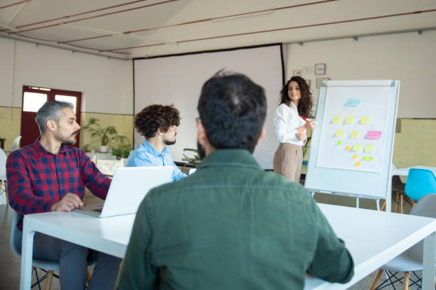 istock Smiling young woman explaining strategy to coworkers 1206155462