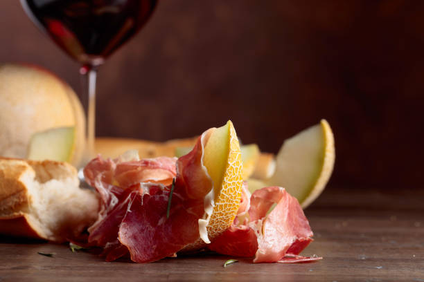 istock Prosciutto with melon and rosemary on a old wooden table. 1206157831