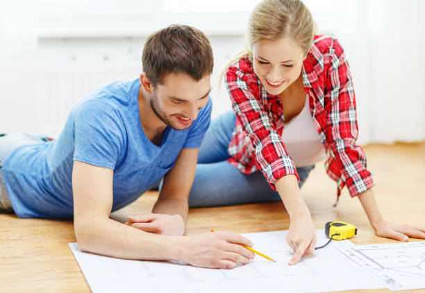 istock smiling couple looking at blueprint at home 1206159630