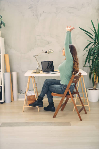 istock Young attractive female doing stretching exercises in modern home office. 1206166379