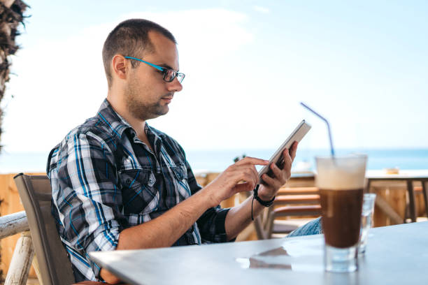 istock Surfing the net and drinking ice coffee at seaside 1206166434