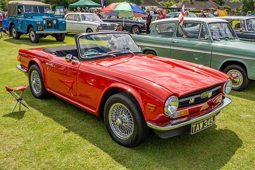 Side view of a vintage Triumph TR6 sports car, in brilliant red, on display at the annual classic car show in Wroxham, Norfolk, UK