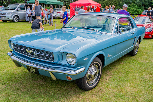 Side view of a blue vintage Ford Mustang on display at the annual classic car show in Wroxham, Norfolk, UK