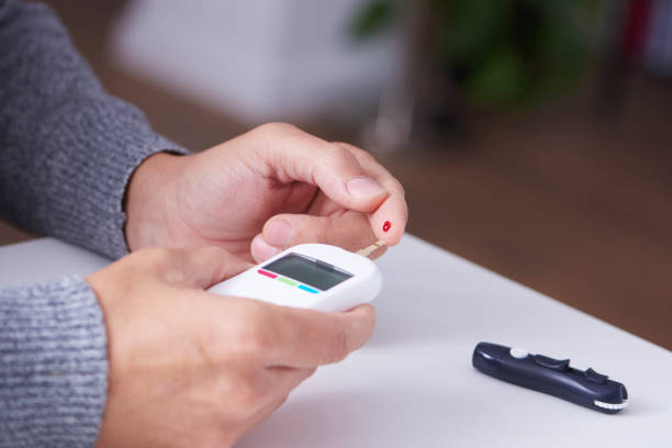 man measuring his blood glucose level closeup of a caucasian man measuring his blood glucose level with a glucose meter hyperglycemia stock pictures, royalty-free photos & images