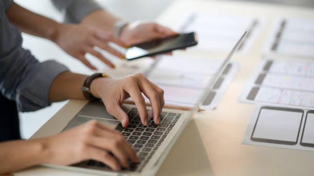 istock Close up view of UI developer typing on laptop and document  while discussing with co worker 1206178594