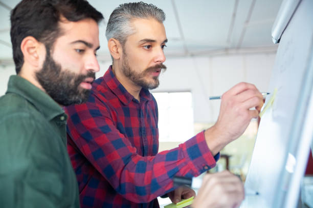 istock Side view of two focused colleagues discussing business plan 1206178738