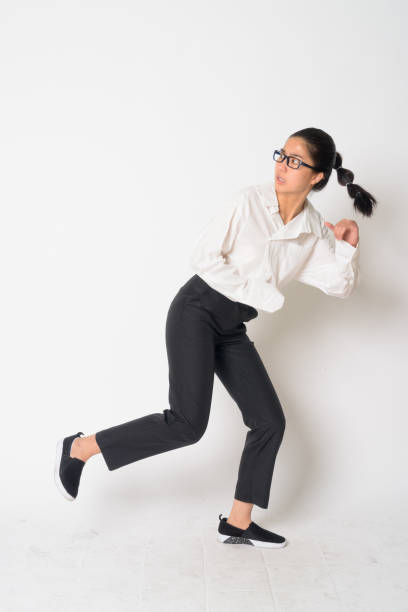 Portrait of stressed young Asian businesswoman with eyeglasses running away Studio shot of young Asian businesswoman with eyeglasses against white background escaping stock pictures, royalty-free photos & images