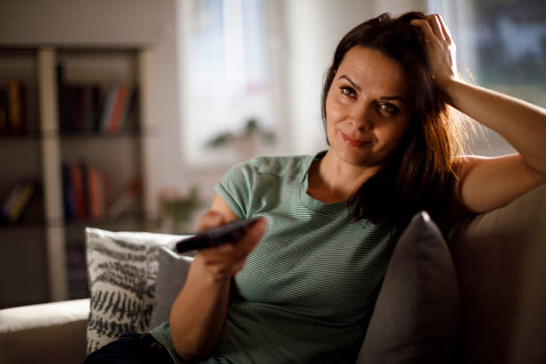 istock Smiling woman watching TV at home 1206187943