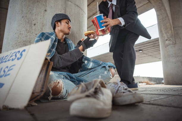 Businessman came up and help homeless man sitting on the floor. Help, money,food donation to vagrant male in the street Businessman came up and help homeless man sitting on the floor. Help, money,food donation to vagrant male in the street begging currency beggar poverty stock pictures, royalty-free photos & images