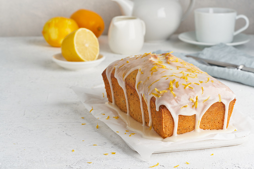 Lemon bread coated with sugar sweet icing. Whole loaf. White background, side view, copy space