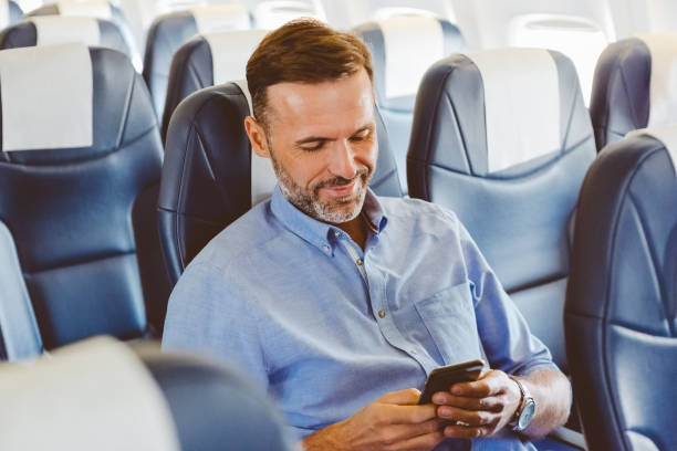 istock Smiling man using smart phone in the airplane 1206203314