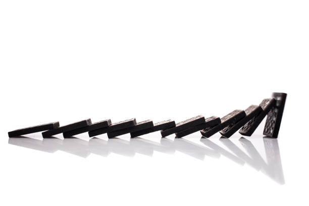 istock Black domino tiles falling in a row, isolated on white 1206203469