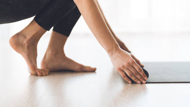 istock Woman rolling exercise yoga mat on wood floor at studio 1206204720