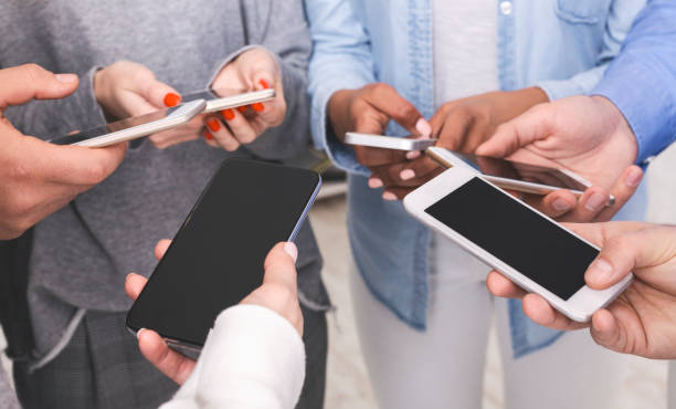 istock Group of unrecognizable friends using smartphones with black screen, sharing media 1206204750