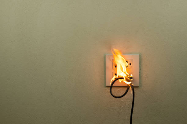 on fire electric wire plug in the receptacle at wall partition, electric short circuit failure resulting in electricity wire burnt - electricity fire circuit board short imagens e fotografias de stock