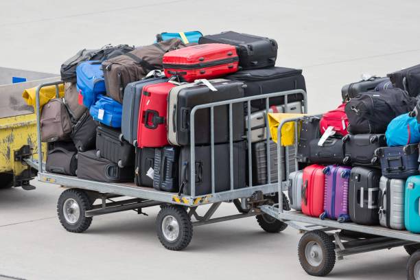 gepäcktransfer im freien auf dem gelände eines flughafens - luggage cart stock-fotos und bilder