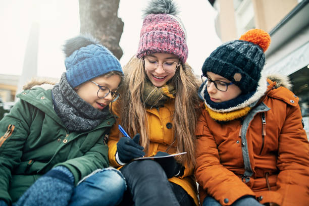 istock Three kids writing postcards on street bench 1206209208