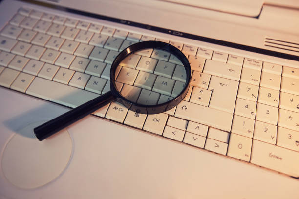 istock Close up of a magnifying glass on an old laptop keyboard. Computer search engine. Browsing network for answer to every question. Finding useful information and data, internet searching concept. 1206212453