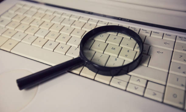 istock Close up of a magnifying glass on an old laptop keyboard. Computer search engine. Browsing network for answer to every question. Finding useful information and data, internet searching concept. 1206212550