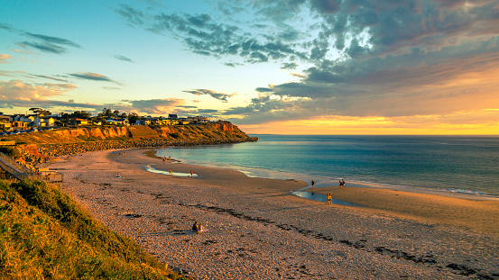 Adelaide, South Australia - October 7, 2018: People walking along the shore while enjoying beautiful sunset at Christies Beach on a warm evening