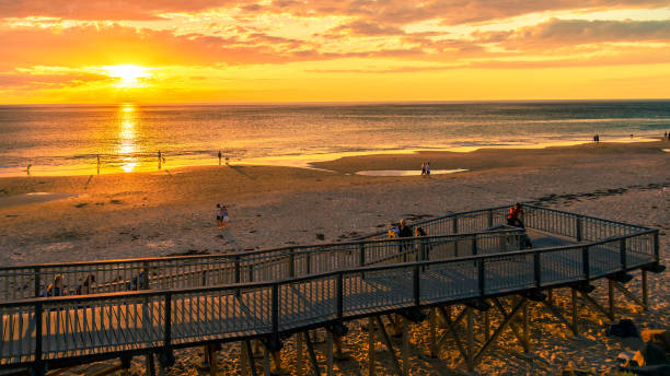 Adelaide, South Australia - October 7, 2018: People walking along the shore while enjoying beautiful sunset at Christies Beach on a warm evening
