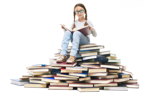 Portrait of cute girl sitting on pile of books and looking at camera