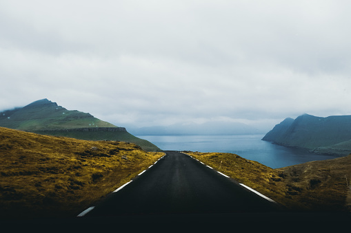 Driving at the panoramic mountain road by car with view of beautiful sea and mountains on Faroe Island, Scandinavia