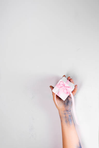 istock Women's blue glittering hands are taking a white gift box. Stone festive background . Presenting or Receiving a gift. Top view. 1206216748