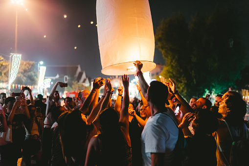 Chiang Mai, Thailand - November 11, 2019: Tourists alike lift their lanterns into the night sky at the Loi Krathong festival in Chiang Mai, Thailand.