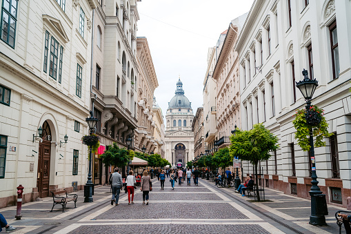 Budapest, Hungary - September 7, 2019. Street leading to neoclassical St. Stephen's Basilica - popular landmark, largest church in Budapest. Downtown pedestrian street with trees, cafes and restaurants.