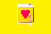 Paper cutout of red heart symbol on a white speech bubble on yellow background. Concept of social media and digital marketing.