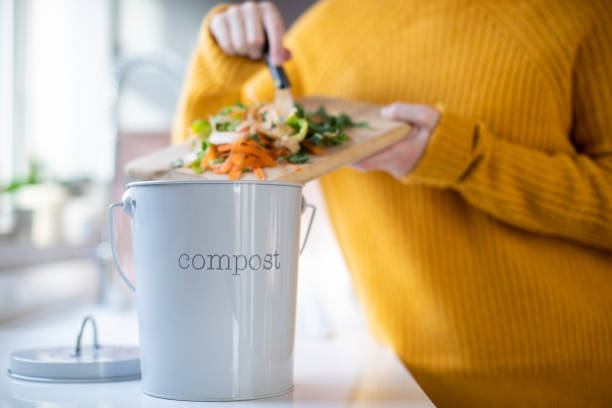 Close Up Of Woman Making Compost From Vegetable Leftovers In Kitchen Close Up Of Woman Making Compost From Vegetable Leftovers In Kitchen leftovers photos stock pictures, royalty-free photos & images