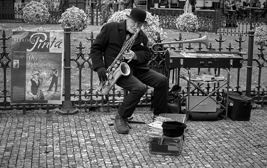 Prague, Czech Republic - March 31 2018: Black and white of an old street musician playing saxophone or sax in the city of Prague. Tourist attraction, live and outdoor performance.